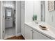Bright bathroom with white cabinets, tile countertops, and a view into another bathroom at 5690 W 80Th Pl # 101, Arvada, CO 80003