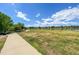 Scenic lake view with paved walking trail, trees, and lush green space under a partly cloudy blue sky at 5690 W 80Th Pl # 101, Arvada, CO 80003