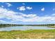 Picturesque water view with grassy shoreline, distant mountains, and a partly cloudy blue sky overhead at 5690 W 80Th Pl # 101, Arvada, CO 80003