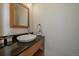 Chic powder room featuring a vessel sink, dark countertop, and a wood-framed mirror at 6637 Berry Bush Ln, Evergreen, CO 80439