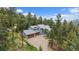 Stunning two-story home with a three-car garage surrounded by lush greenery and a long driveway at 6637 Berry Bush Ln, Evergreen, CO 80439