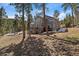 Back exterior of a two-story home with a deck and wooded yard at 6637 Berry Bush Ln, Evergreen, CO 80439