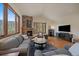Inviting living room featuring a stone fireplace, hardwood floors, and large windows at 6637 Berry Bush Ln, Evergreen, CO 80439
