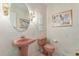 Vintage powder room with pink fixtures, framed art, and round mirror at 20886 Parliament Pl, Parker, CO 80138