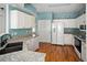 Bright kitchen with white cabinetry, laminate counters, hardwood floors, and modern appliances at 9150 Gale Blvd # 1, Thornton, CO 80260
