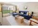 Bright living room with a plush blue sectional, neutral rug, and sliding glass doors to a patio at 2 Adams Street # 108, Denver, CO 80206