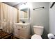 Well-lit bathroom featuring a toilet, sink, vanity and shower with floral curtain at 130 N 8Th Ave, Brighton, CO 80601