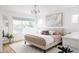 Bright bedroom featuring a large window, chandelier, neutral-toned bedding, and modern decor at 2685 S Acoma St, Denver, CO 80223