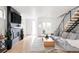 Modern living room with a gray sofa, stylish fireplace, wood floors, and an open staircase at 2685 S Acoma St, Denver, CO 80223