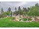 Landscaped backyard featuring a pond and tennis court, surrounded by lush greenery and trees at 34650 Sleeping Fox Trl, Evergreen, CO 80439