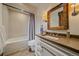 Bright bathroom featuring a shower over tub with white tiling and a wood framed mirror over the vanity at 34650 Sleeping Fox Trl, Evergreen, CO 80439