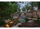 Beautifully landscaped backyard featuring a serene stream, lush greenery, and charming stone pathways at 34650 Sleeping Fox Trl, Evergreen, CO 80439