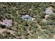 An aerial view of a house with a dark green roof surrounded by lush green trees and other homes at 6723 Perry Park Blvd, Larkspur, CO 80118