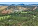 An aerial view showcasing a lake, golf course, and rock formations nestled among pine trees and mountains at 6723 Perry Park Blvd, Larkspur, CO 80118