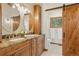 Bathroom featuring double sinks with granite countertop, wooden cabinets, and a sliding barn door at 6723 Perry Park Blvd, Larkspur, CO 80118