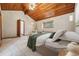 Cozy bedroom featuring a wood-paneled ceiling, a comfortable bed with soft green accents, and natural light from a side window at 6723 Perry Park Blvd, Larkspur, CO 80118