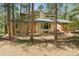 Tan two-story house with a green roof and a balcony surrounded by tall pine trees in a sunny, wooded area at 6723 Perry Park Blvd, Larkspur, CO 80118