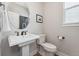 Clean and well-lit powder room with pedestal sink, round mirror, and neutral decor at 52 Simmental Loop, Castle Rock, CO 80104
