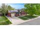 Charming two-story home features red brick, solar panels, attached garage, long driveway and a well-maintained front lawn at 821 Clarkson Ct, Denver, CO 80229
