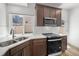 Stylish kitchen featuring dark wood cabinets, stainless steel appliances, quartz countertops, and natural light at 1164 Sugarloaf Ln, Erie, CO 80516