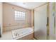 Bright bathroom with a glass block window, jacuzzi tub, and glass shower door at 16029 W 75Th Pl, Arvada, CO 80007