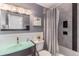 Modern bathroom with gray walls, glass vessel sink, and tiled shower with curtain at 16029 W 75Th Pl, Arvada, CO 80007