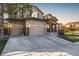 Inviting home featuring a three-car garage, stone accents, and manicured lawn at sunset at 15310 E 108Th Way, Commerce City, CO 80022