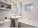 Bright bathroom has a white pedestal sink, subway tile, shower-tub, and a window at 4534 W 65Th Ave, Arvada, CO 80003