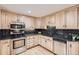 Well-lit kitchen features wood cabinets, black countertops, and stainless steel appliances at 4534 W 65Th Ave, Arvada, CO 80003