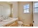 Bright bathroom with a white tile countertop, wood cabinets, and a window with natural light at 1864 Malibu Ct, Fort Lupton, CO 80621