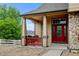 Covered front porch showcasing a red door, stone accents, and seating area at 1864 Malibu Ct, Fort Lupton, CO 80621