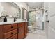 Bathroom featuring a stylish vanity, framed mirror and a walk-in shower with marble tiling at 1071 Oak Cir, Lakewood, CO 80215