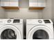 Convenient laundry room featuring a modern washer and dryer set and white cabinets at 1071 Oak Cir, Lakewood, CO 80215