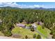 Aerial view of a property showcasing a house, detached garage, mature trees, and a scenic mountain backdrop at 8045 S Wagon Wheel Rd, Morrison, CO 80465