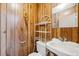 Compact bathroom featuring wood paneled walls, toilet, and sink at 8045 S Wagon Wheel Rd, Morrison, CO 80465