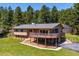 Charming home featuring a large wooden deck, stone accents, and an attached garage, all surrounded by a green lawn at 8045 S Wagon Wheel Rd, Morrison, CO 80465