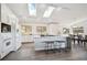 Bright kitchen featuring a granite island with seating, white cabinetry, and stainless steel appliances with skylights above at 8045 S Wagon Wheel Rd, Morrison, CO 80465