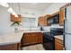 Functional kitchen area with wood cabinets, stainless steel sink, and black appliances at 8045 S Wagon Wheel Rd, Morrison, CO 80465