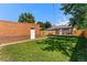 A spacious backyard features lush grass, a wooden fence, and a charming brick outbuilding at 2821 N Harrison St, Denver, CO 80205