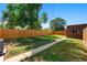 A spacious backyard features lush grass, a wooden fence, and a charming brick outbuilding at 2821 N Harrison St, Denver, CO 80205