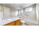 Bright bathroom featuring a large mirror, tub with shower, accessible grab bar, and light wood vanity at 5308 S Ukraine St, Aurora, CO 80015