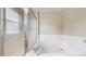 Bright bathroom featuring a whirlpool tub with white tile and a glass-enclosed shower with natural light at 5308 S Ukraine St, Aurora, CO 80015