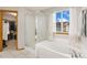 Bathroom featuring a soaking tub, glass enclosed shower, and natural light at 16478 Marion St, Thornton, CO 80602