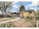 Backyard featuring a yellow house with black trim, lawn, and mature trees at 5008 Alcott St, Denver, CO 80221