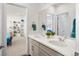 Bright bathroom featuring a double vanity with framed mirror and a view to an open doorway at 5861 Tesoro Pt, Parker, CO 80134
