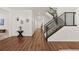 Spacious hallway with wood floors leads to a staircase with black metal railings at 5861 Tesoro Pt, Parker, CO 80134