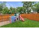 Fenced backyard features a play structure and lush green grass, perfect for outdoor fun and relaxation at 2967 Olive St, Denver, CO 80207