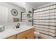 Neutral bathroom with white countertop and wooden vanity, accented with a decorative mirror and patterned shower curtain at 2967 Olive St, Denver, CO 80207