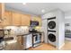 Well lit kitchen with stainless steel appliances and stacked washer and dryer, complemented by stylish cabinets at 2967 Olive St, Denver, CO 80207