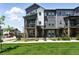 Charming gray townhome featuring a balcony, a well-manicured lawn, and a black metal fence at 6988 Ipswich Ct, Castle Pines, CO 80108